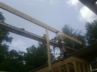 Carpenter setting a ridge beam over a new addition frame — Ice Dam Removal by Roofing Brothers in Mc Farlan
