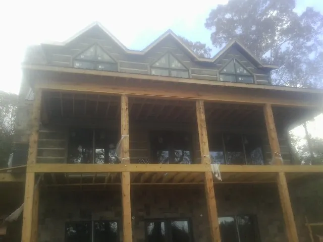 Dormers and porch framing on a large log home under construction — Roof Coating work by our crew in Mc Farlan