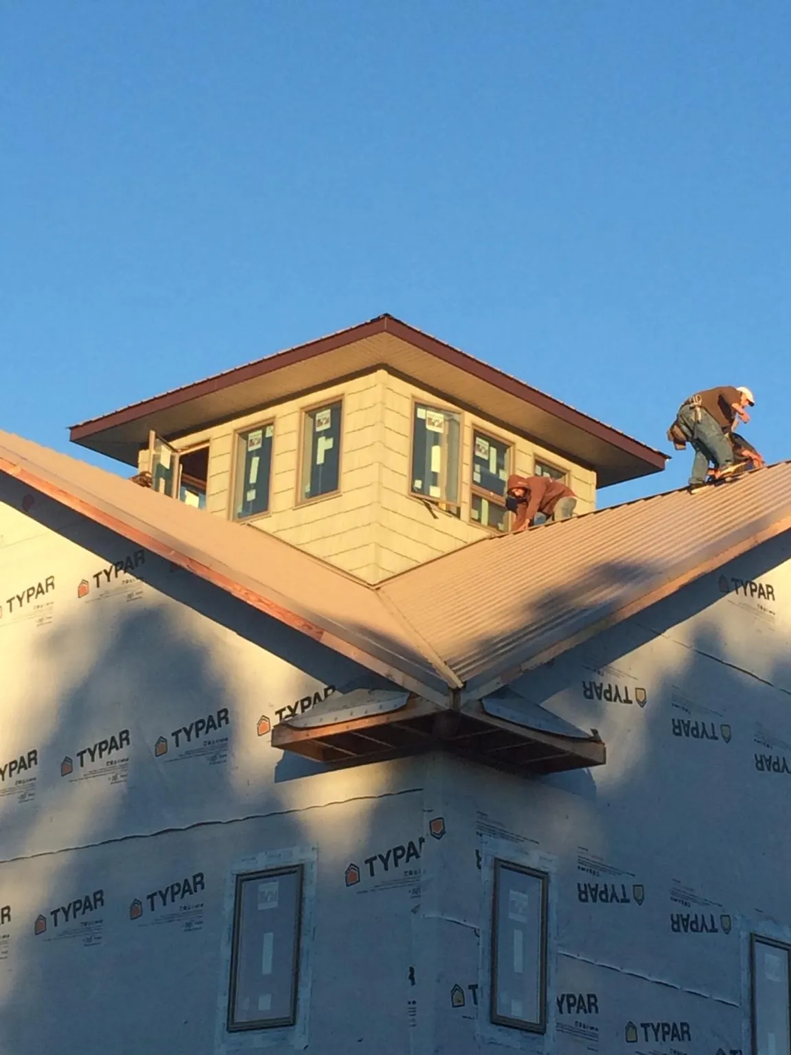 Roofers working around a rooftop cupola on a new metal roof at sunset — Roof Waterproofing in Mc Farlan by Roofing Brothers